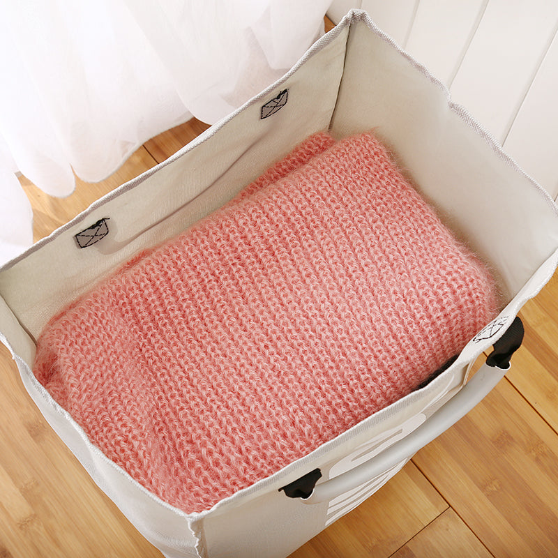 Open foldable fabric laundry hamper with pink knitted item inside